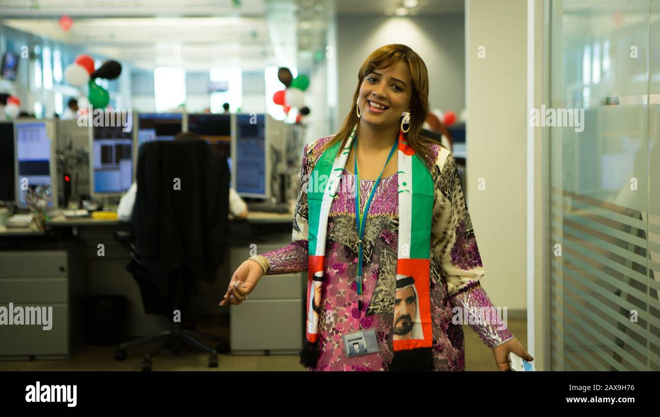 Woman with UAE National Day Scarf and balloons at office, Dubai, United Arab Emirates. Stock Photo