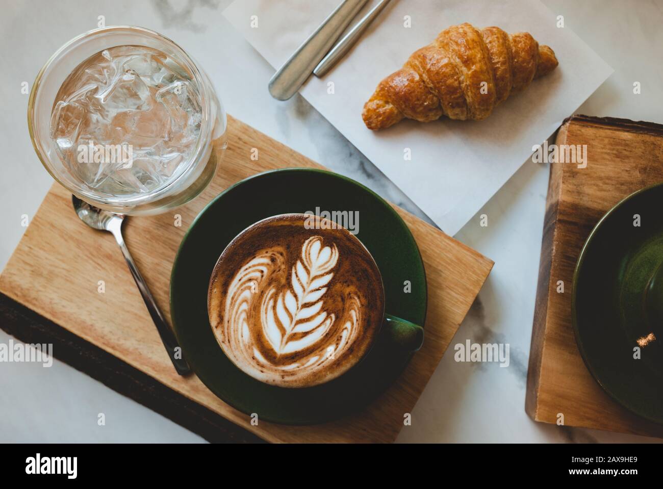 Hot coffee cappuccino latte art serve with croissant in morning worm lighting. Stock Photo