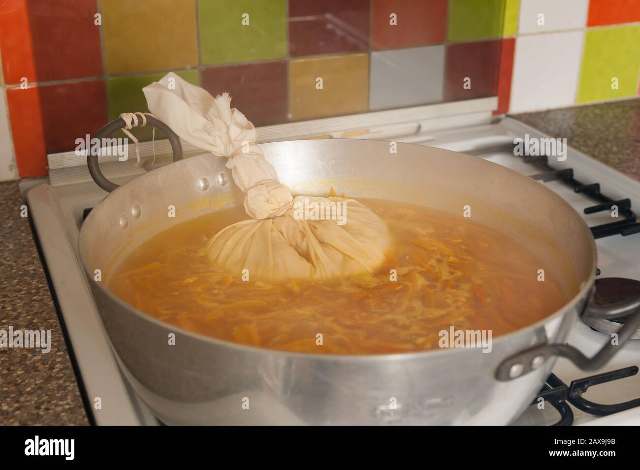 Boiling down Seville oranges in a large jam or marmalade making pan simmering off excess water with muslin bag containing source of pectin seeds pips Stock Photo