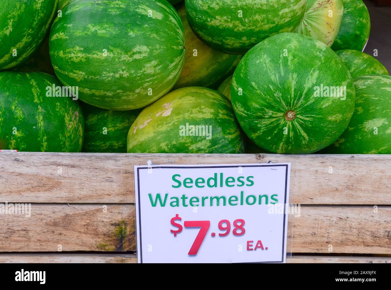 Seedless watermelons in wooden crate with price tag label at farmer