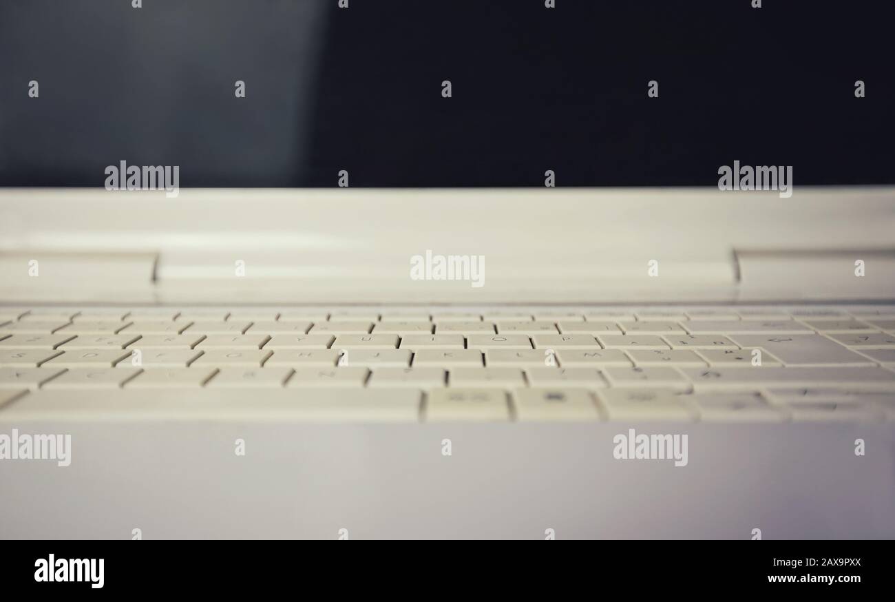 Close up of retro white laptop keyboard. Old computer background, keypad pattern texture and black screen. Stock Photo
