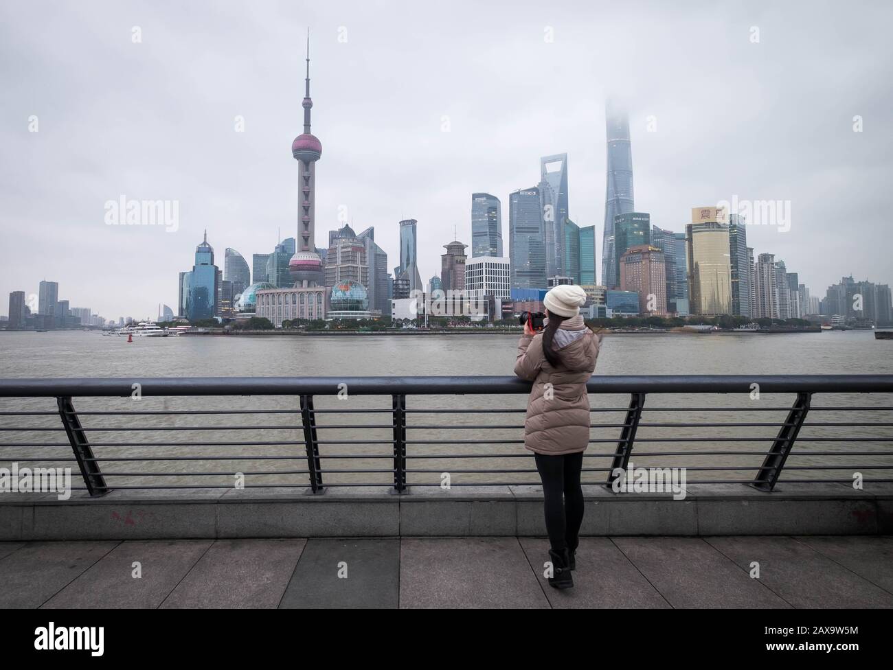 SHANGHAI, CHINA - JANUARY 09 2020: The unspecific girl at the Shanghai Waitan "The Bund" at the viewpoint.  This here is the famous for the traveler. Stock Photo