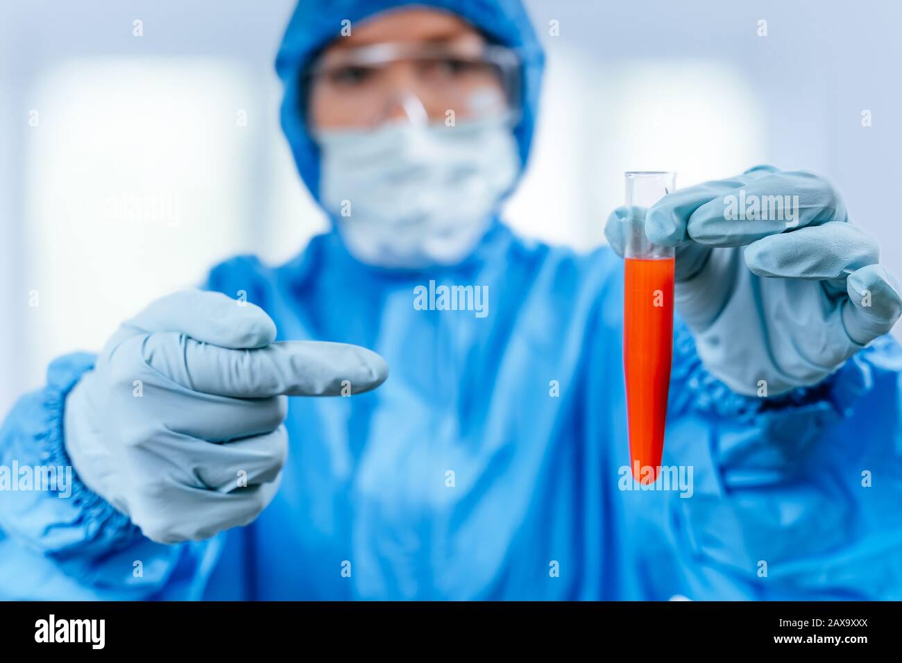 Medic in hazmat protective suit holds a test tube with a coronavirus positive blood sample from Wuhan, China. 2019 nCoV pandemic. stop coronavirus Stock Photo