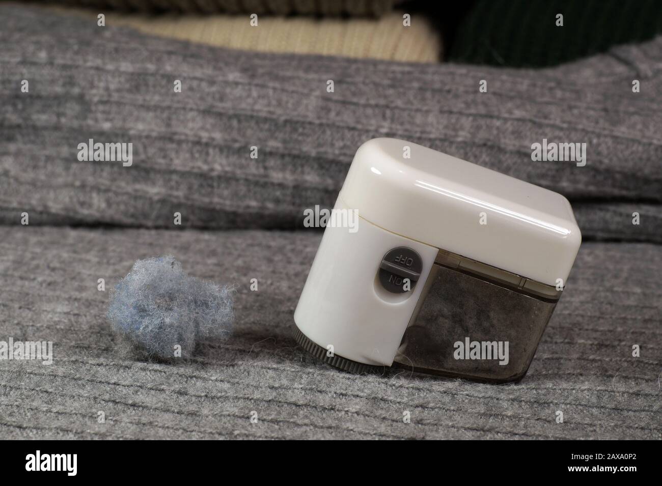 Removing lint (pilling) from the sweater. Device and collected lint. Stock Photo