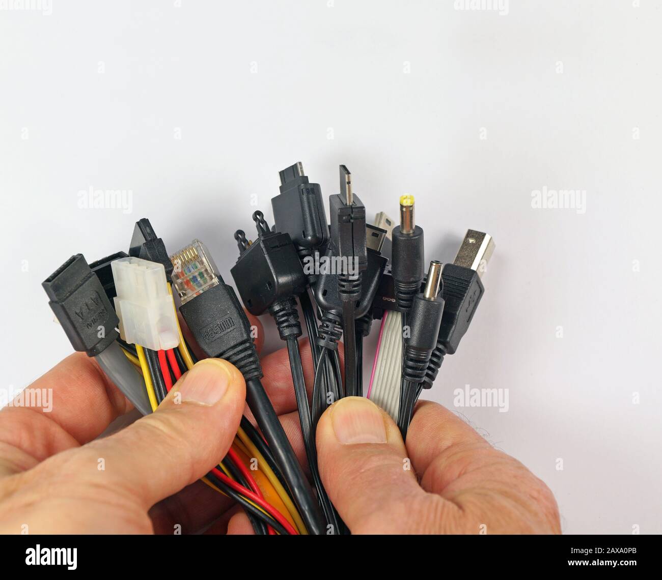 The man holds a dozen or so various plugs for electronic devices in his hands. Stock Photo