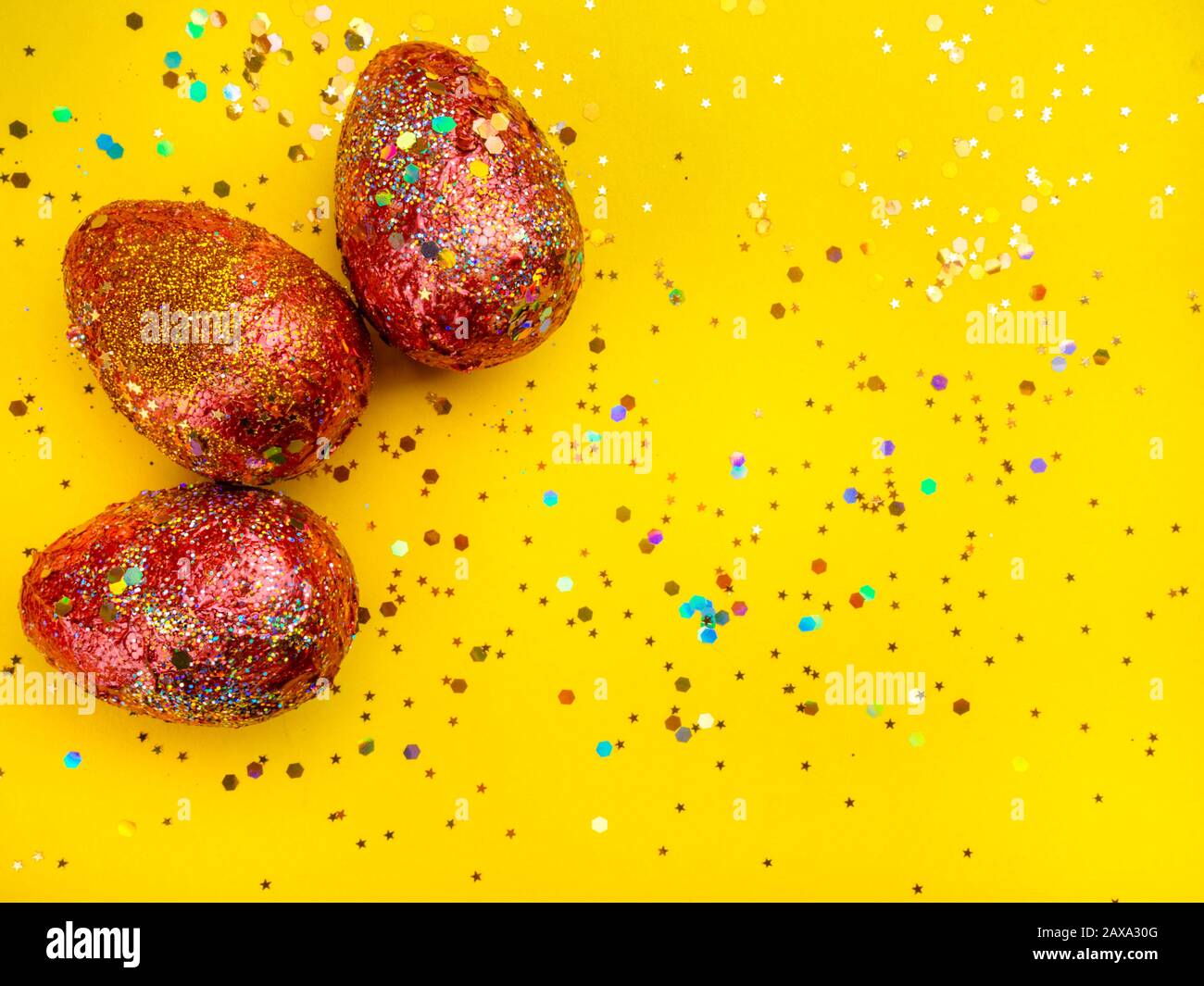 Premium gold Set of 3 golden red easter eggs painted with innovative acrylic on yellow background Ester concept. Top view Stock Photo