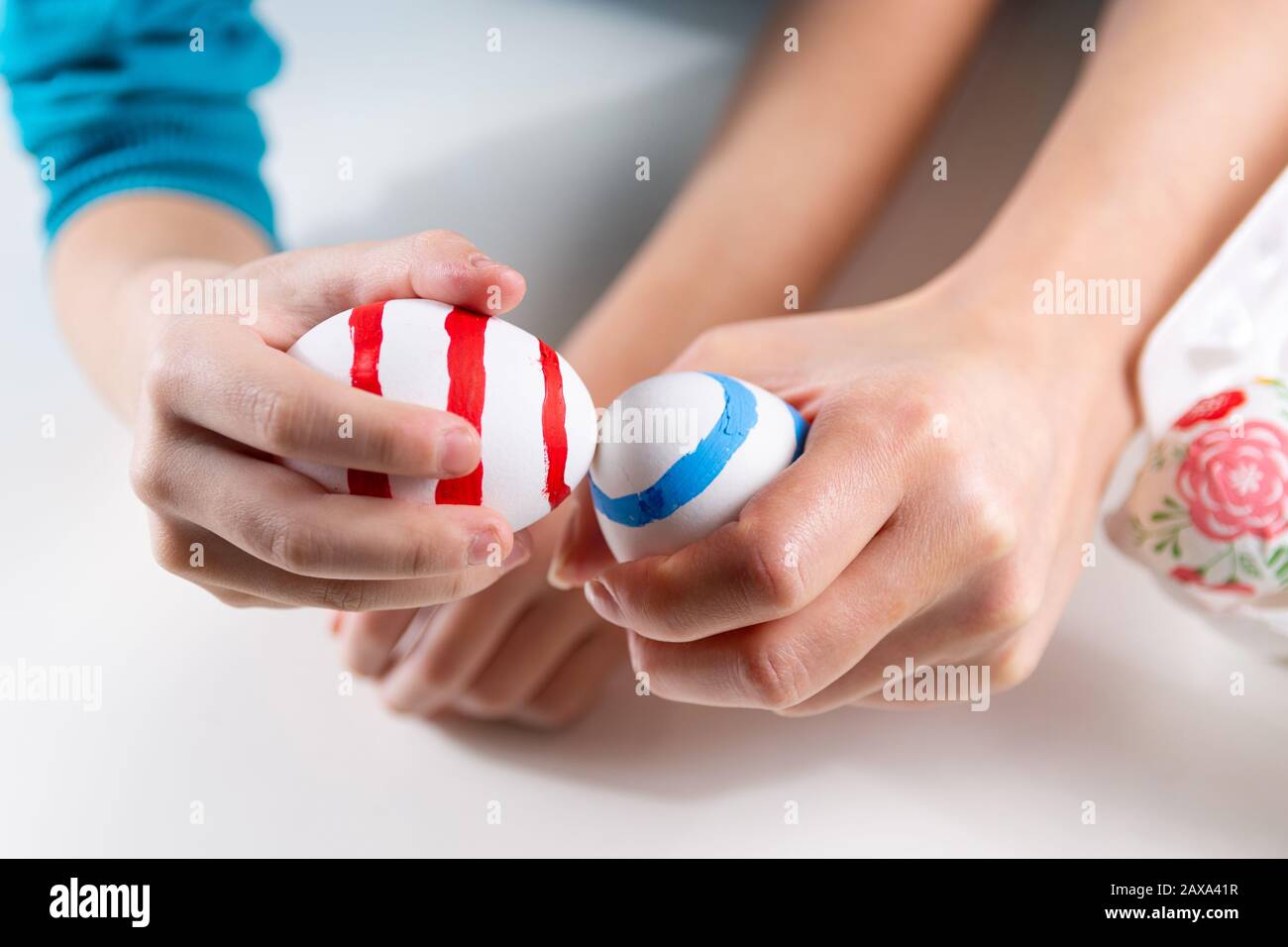 Child hands with colored Easter eggs knocking. Ready for egg tapping indoor at home. Happy Easter orthodox holiday and ritual concept. Close up Stock Photo