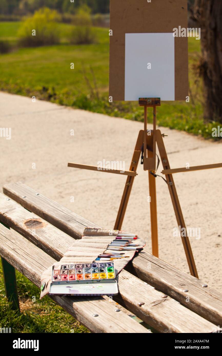 Wooden easel with clean paper and art supplies outdoors Stock Photo Alamy