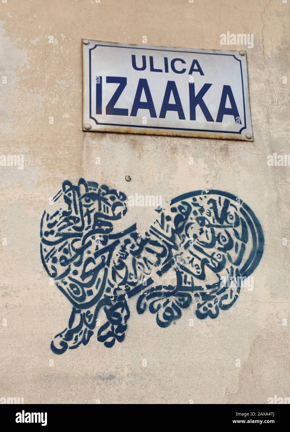 Cracow. Krakow. Poland. Kazimierz, former Jewish district. The Islamic Shiite Calligraphy stencil graffiti under tle plate with the name Isaac Street. Stock Photo