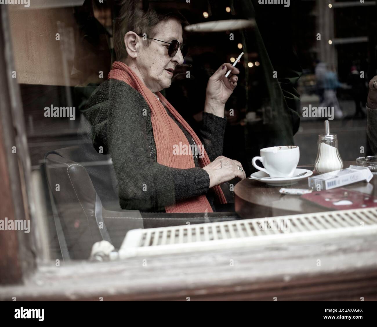 Belgrade, Serbia, Feb 7, 2020: An elderly lady enjoying coffee and cigarettes in one of downtown cafes Stock Photo