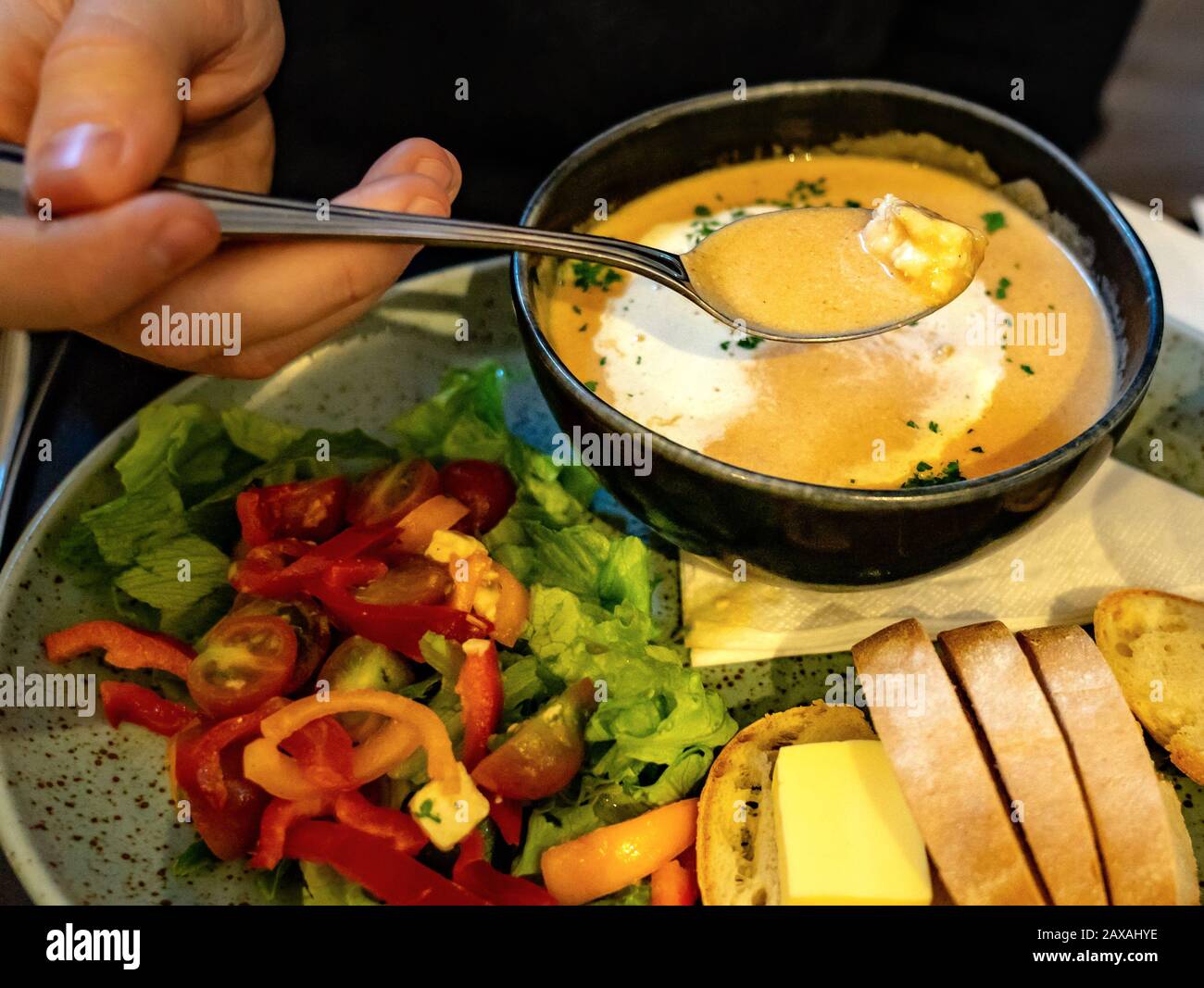 man eating lobster cream soup with salad and butter bread in restaurant Stock Photo