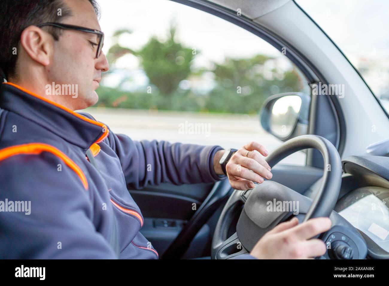 Delivery man driving a car and looking on the watch Stock Photo