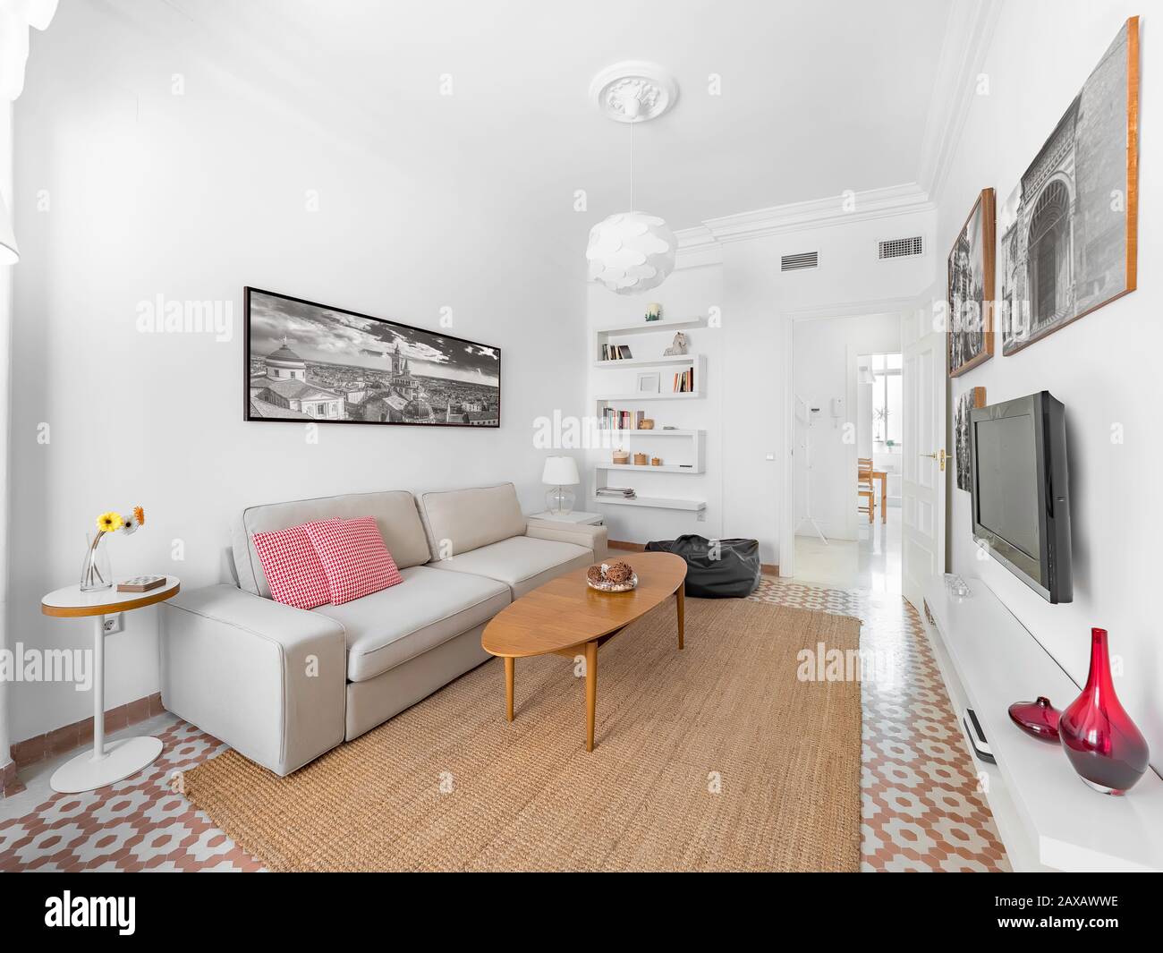 Confortable stylish bright living room with natural ratan carpet, sofa, wooden table, pictures and plants. Spacious modern interior in earthy colors Stock Photo