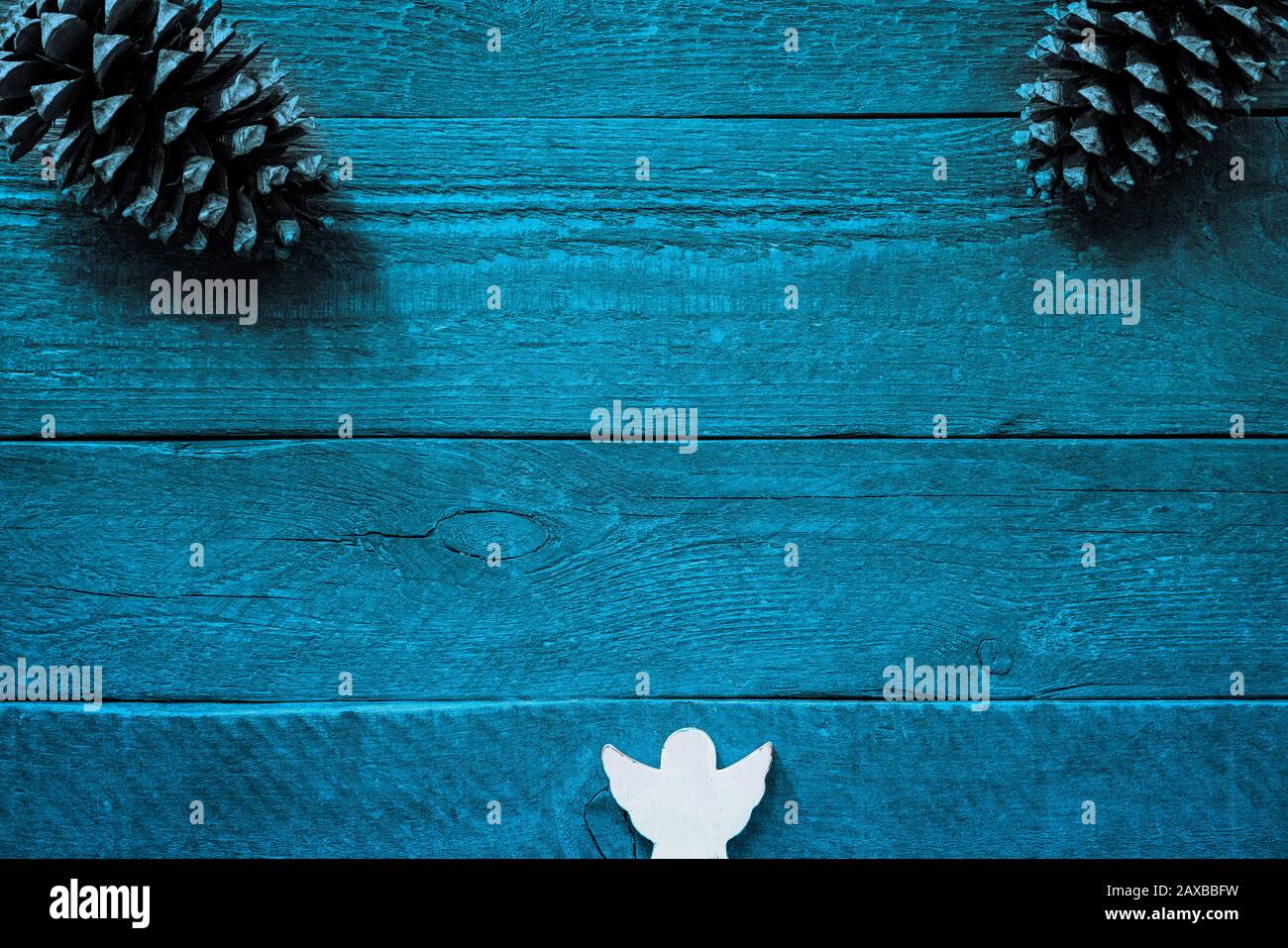 Colourful blue wooden planks with structure and copy space, two fir cones and an angel Stock Photo