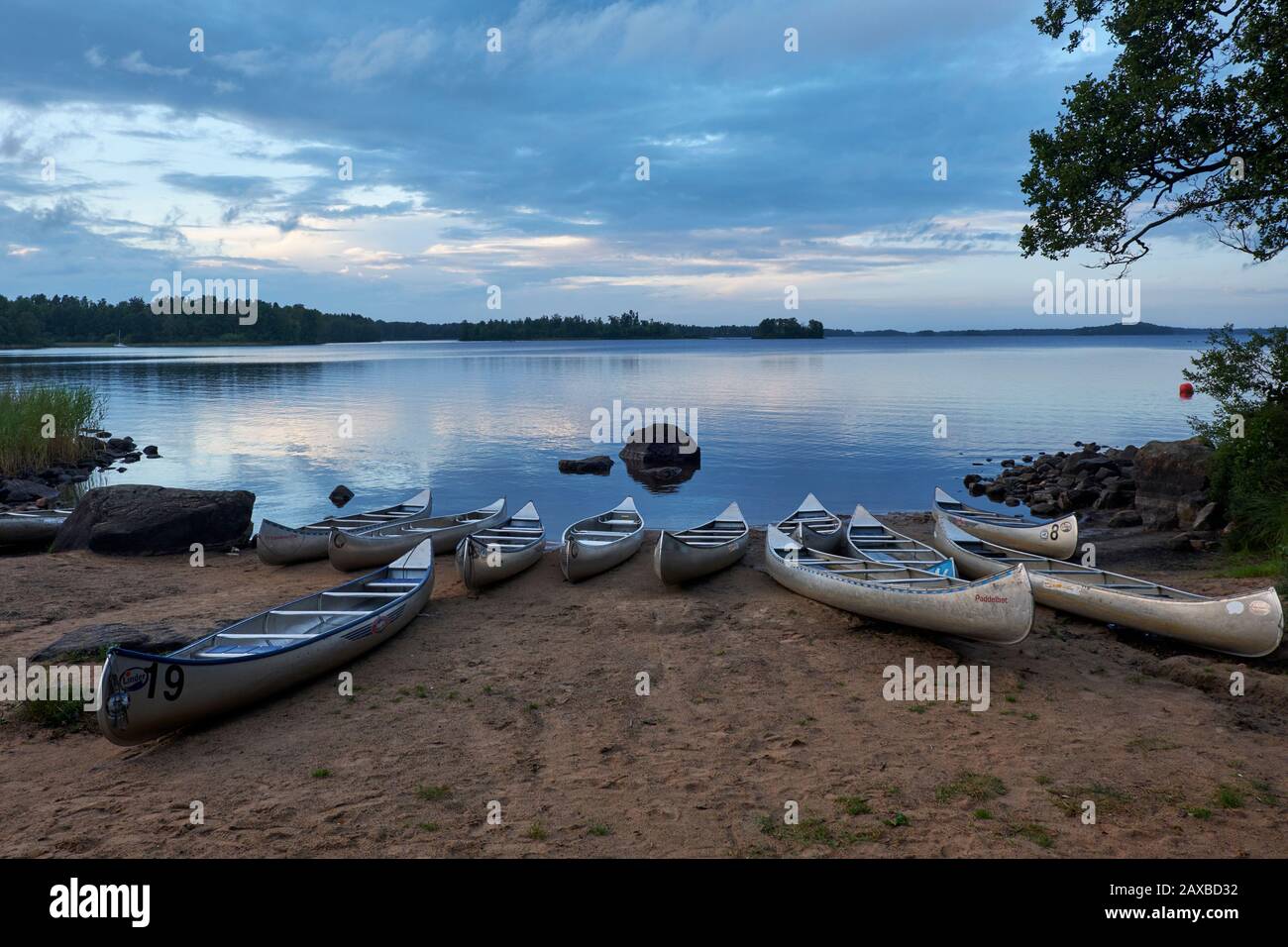 Beached canoe's and kayak's on the shore of Lake Möckeln, Sweden at dusk Stock Photo