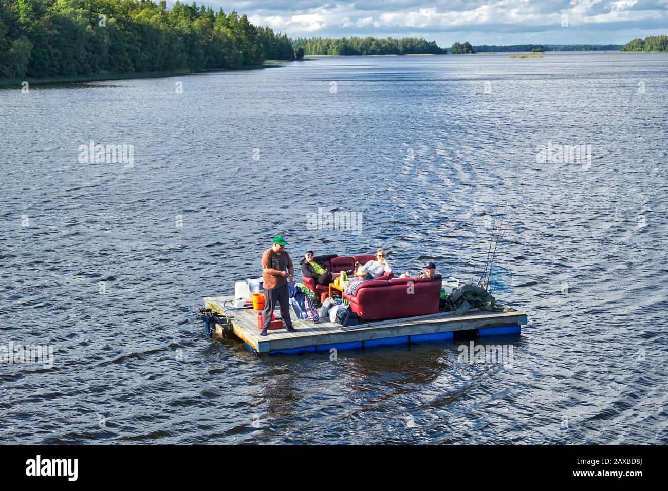 Group of friends fishing and relaxing on a homemade wooden raft floating on Lake Åsnen Stock Photo