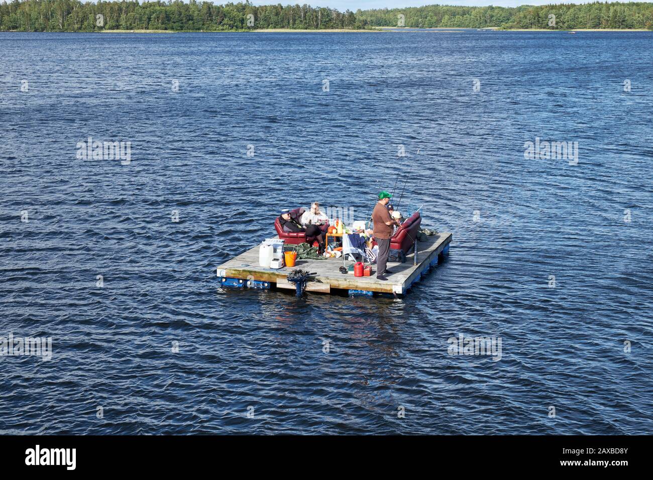 Group of friends fishing and relaxing on a homemade wooden raft floating on Lake Åsnen Stock Photo