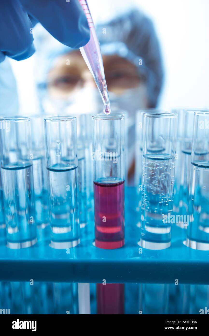 Laboratory pipette in a doctor's hand dripping liquid into a test tube ...