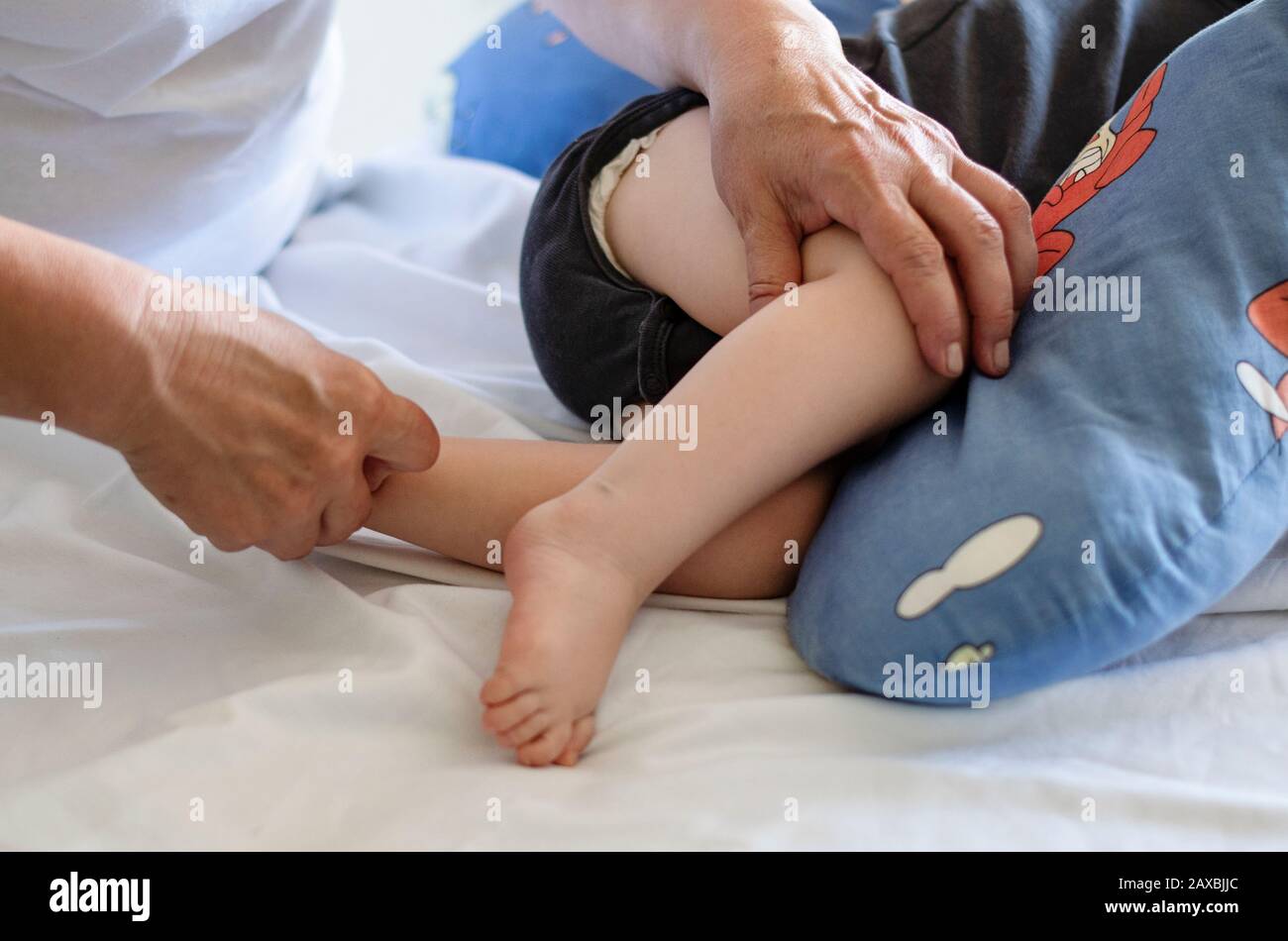 Baby having foot massage in a rehabilitation centre. Little child on therapy. Massage therapist massaging a baby patient. Stock Photo