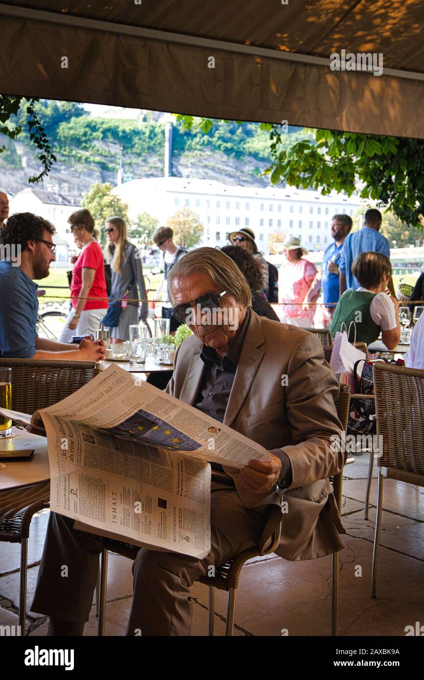 Well dressed man reading newspaper on the terrace at the Cafe Bazar, Salzburg, Austria. Stock Photo