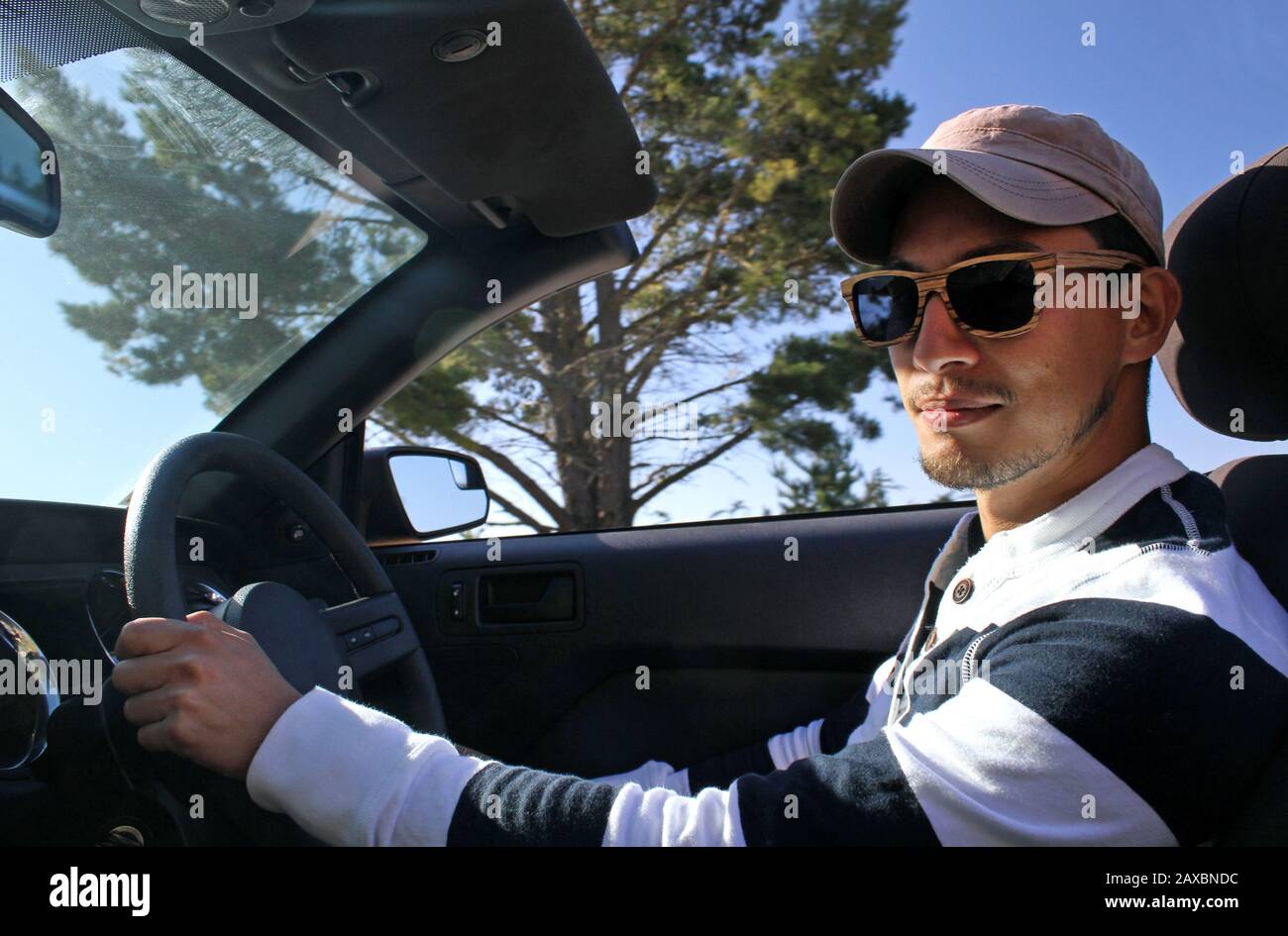 Man with wooden sunglasses and a cap driving a cabriolet Stock Photo - Alamy