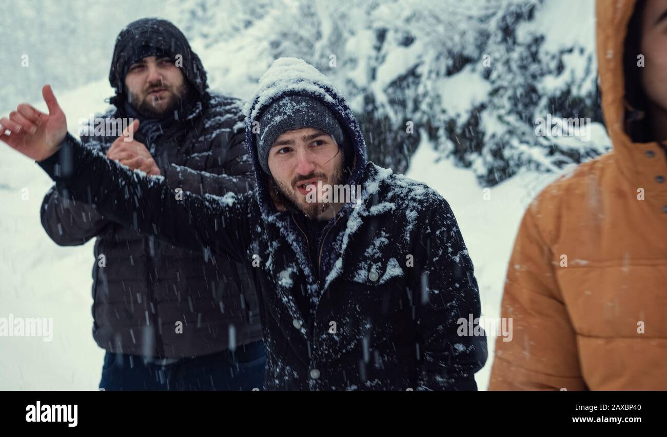 While it is snowing on a winter day, the cold men makes a hand sign to stop the bus.Transportation concept in winter. Stock Photo