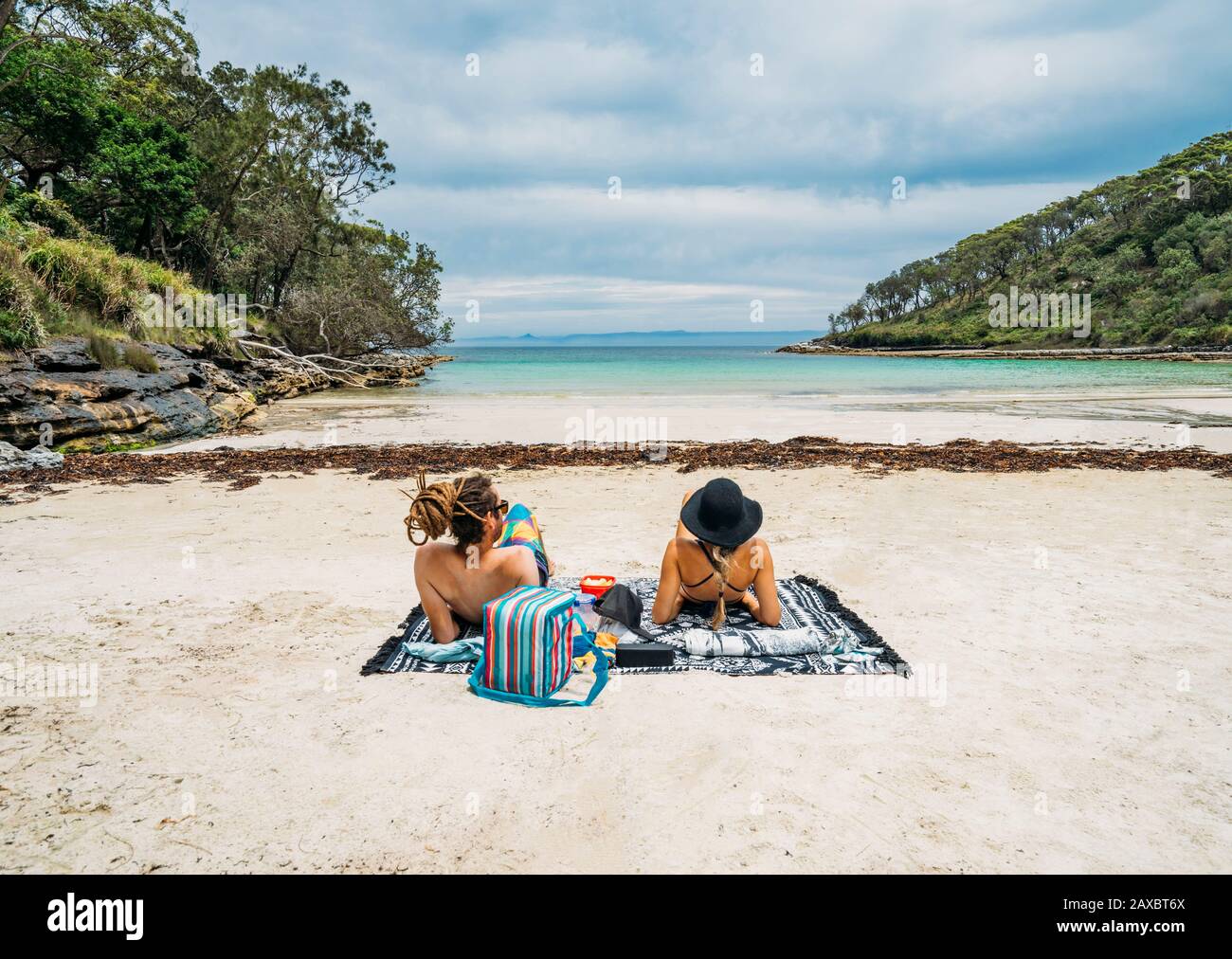 Couple sunbathing on remote tropical ocean beach Jervis Bay Australia Stock Photo