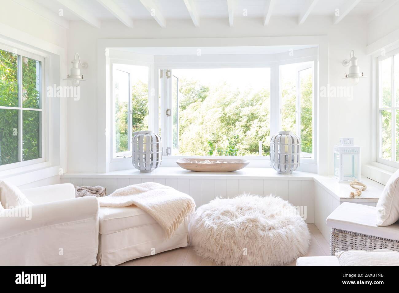 White home showcase sitting area with windows open to garden Stock Photo