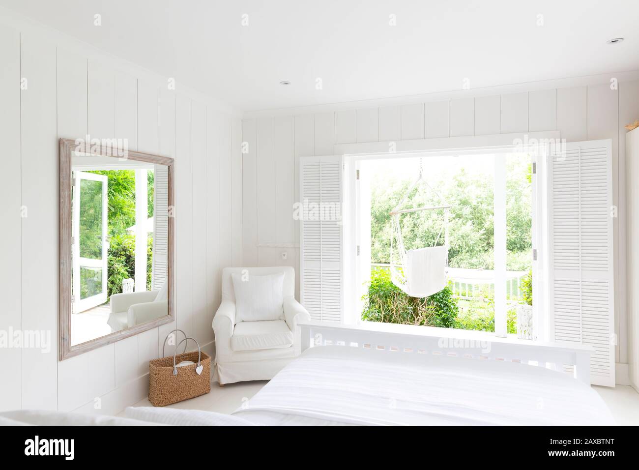 White, tranquil home showcase bedroom open to sunny patio with hammock Stock Photo
