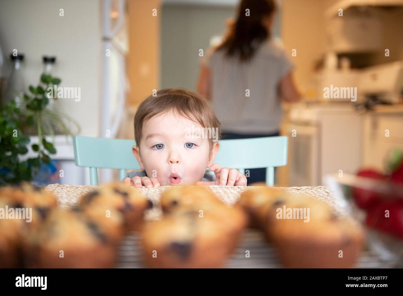 Cute excited girl starting at fresh homemade muffins Stock Photo
