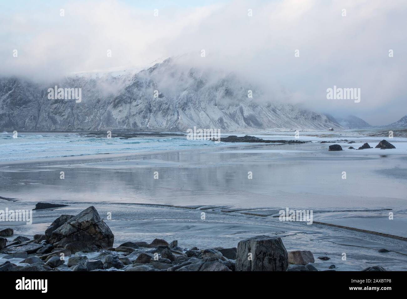 Majestic snow covered mountain behind ocean Skagsanden Lofoten Norway Stock Photo