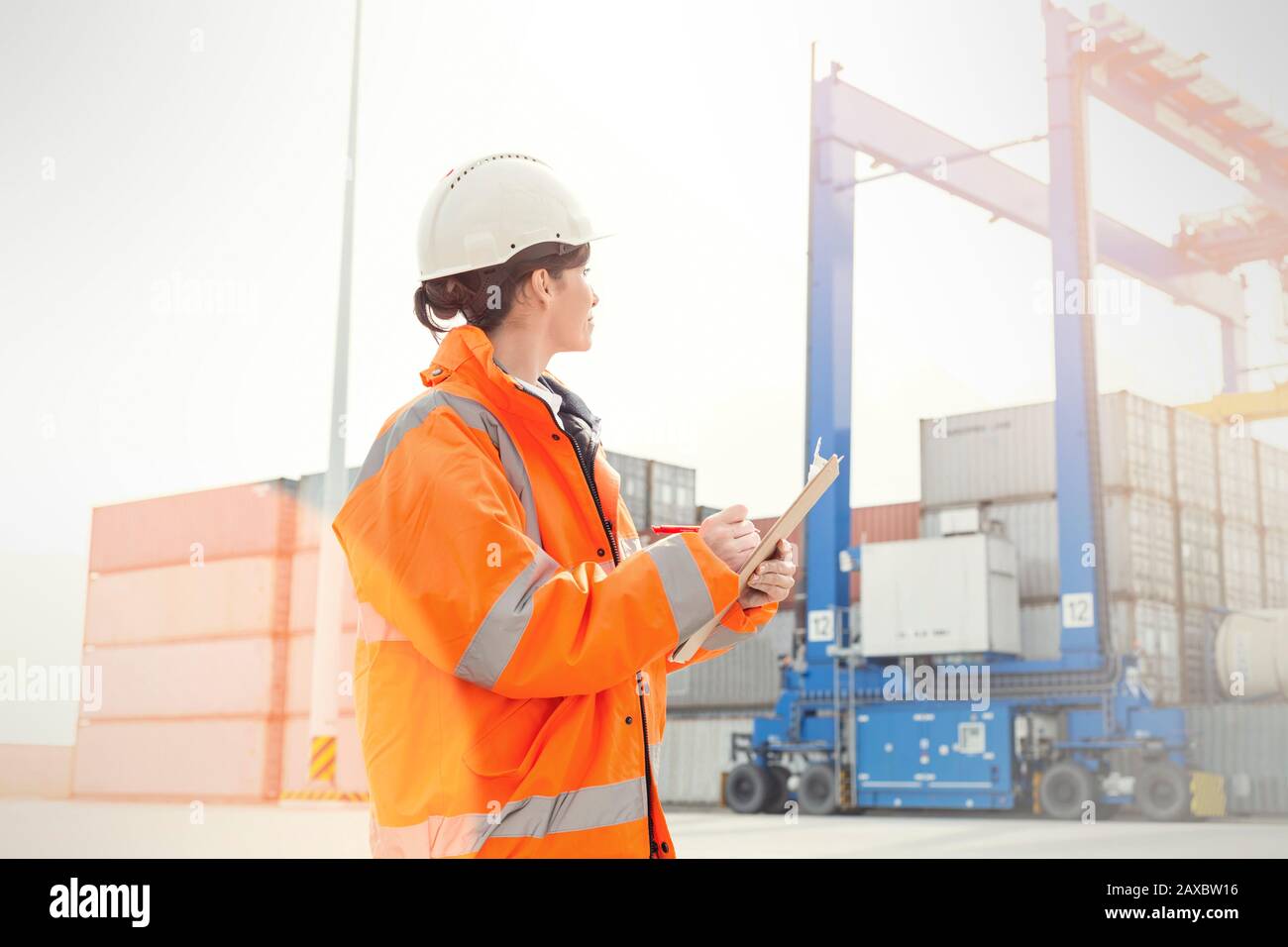 Female dock manager with clipboard watching cargo containers Stock Photo