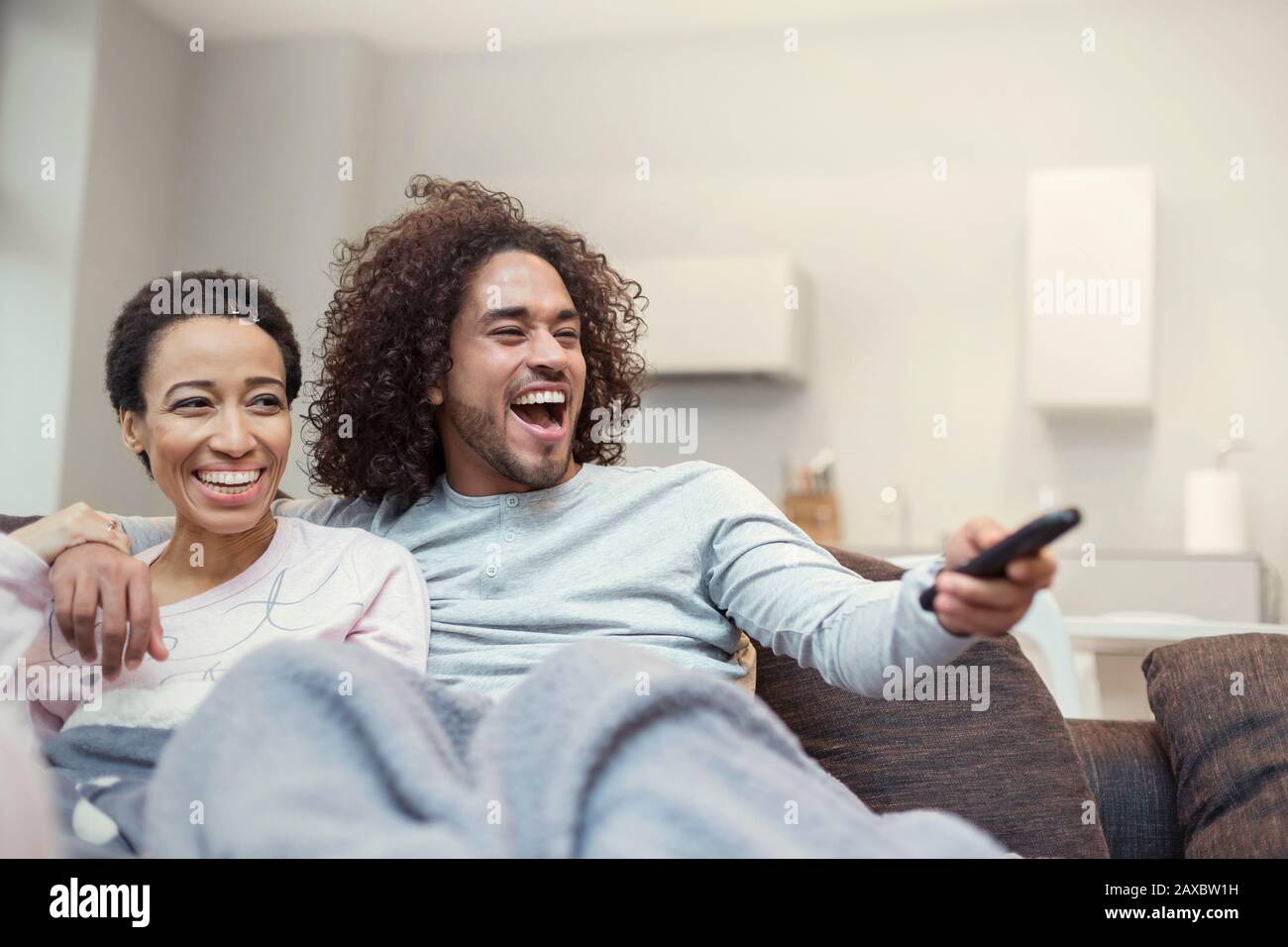 Happy couple relaxing, watching TV on living room sofa Stock Photo Alamy
