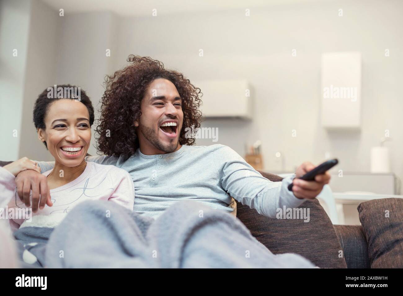 Happy couple relaxing, watching TV on living room sofa Stock Photo