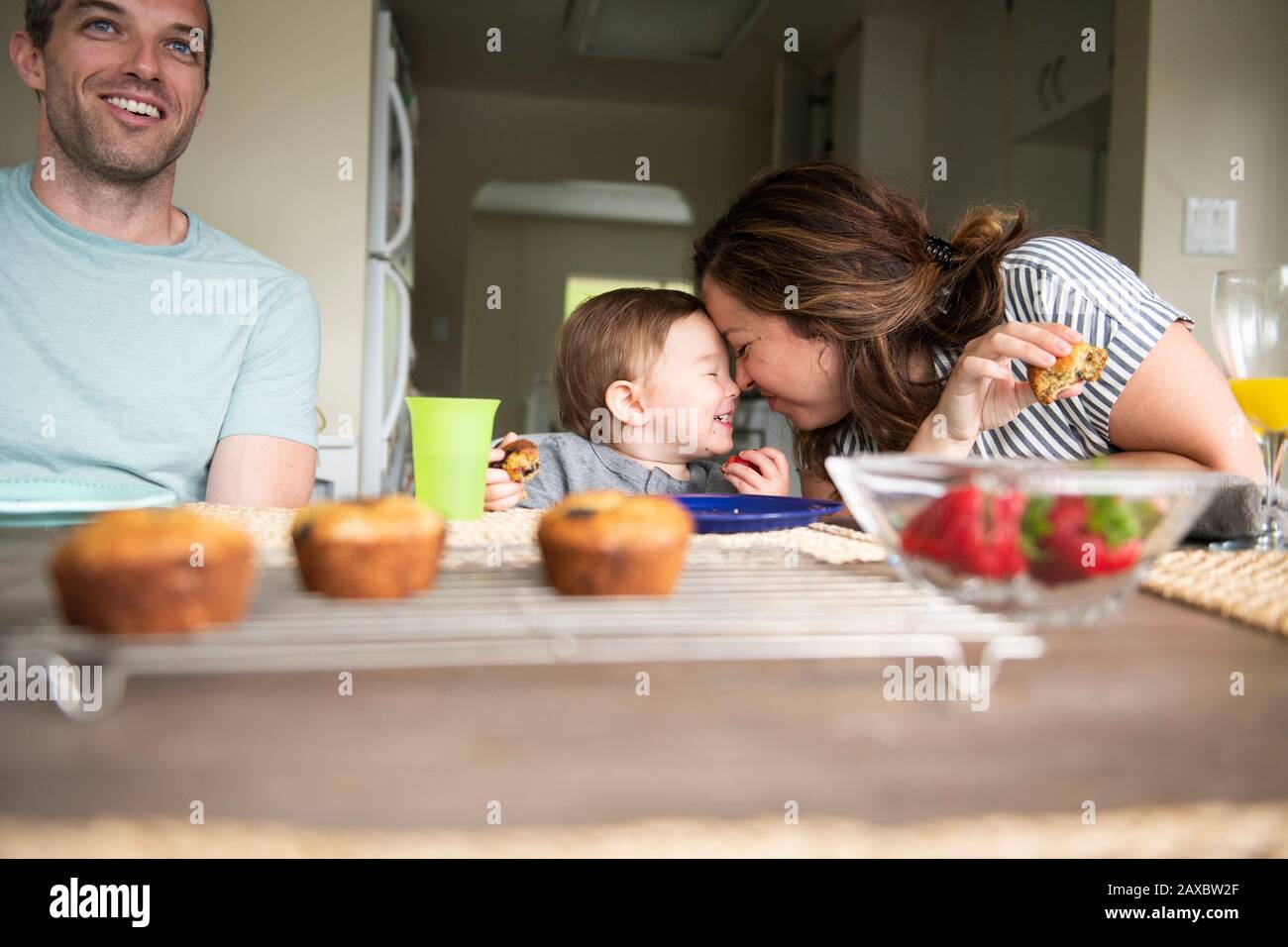 Happy mother and daughter rubbing noses at kitchen table Stock Photo