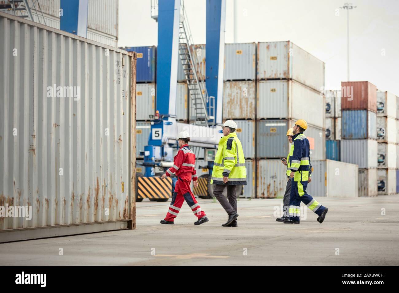 Dock workers walking along cargo containers at shipyard Stock Photo