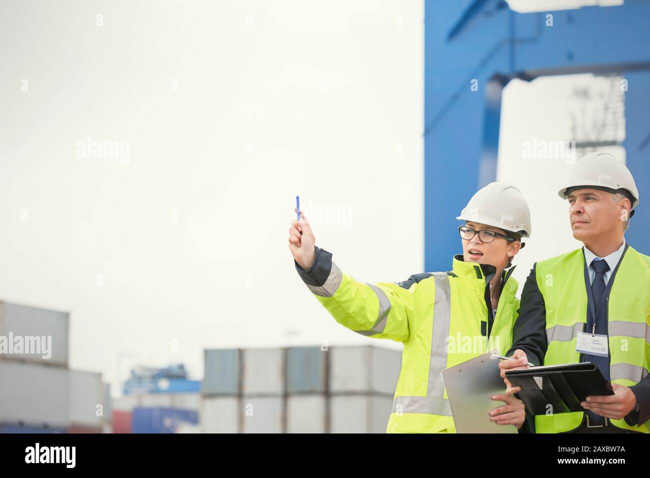Dock worker and manager with clipboard talking at shipyard Stock Photo