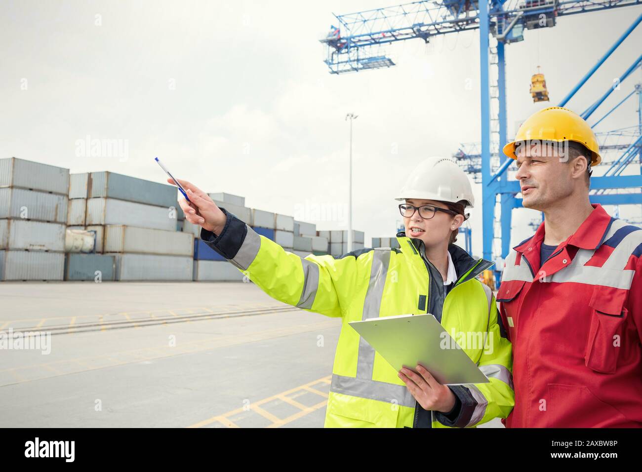 Dock workers with clipboard talking at shipyard Stock Photo