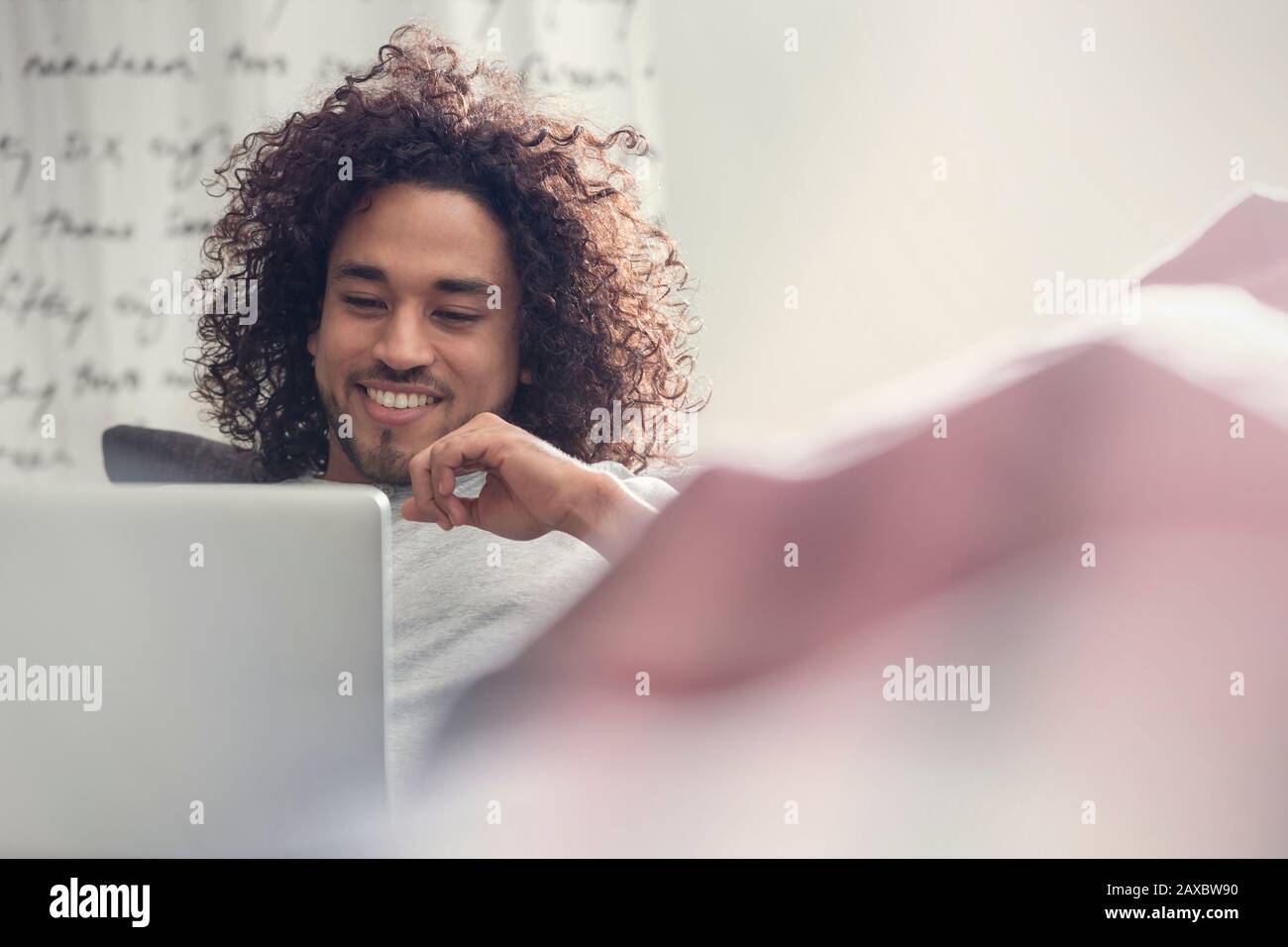 Smiling young man using laptop on sofa Stock Photo