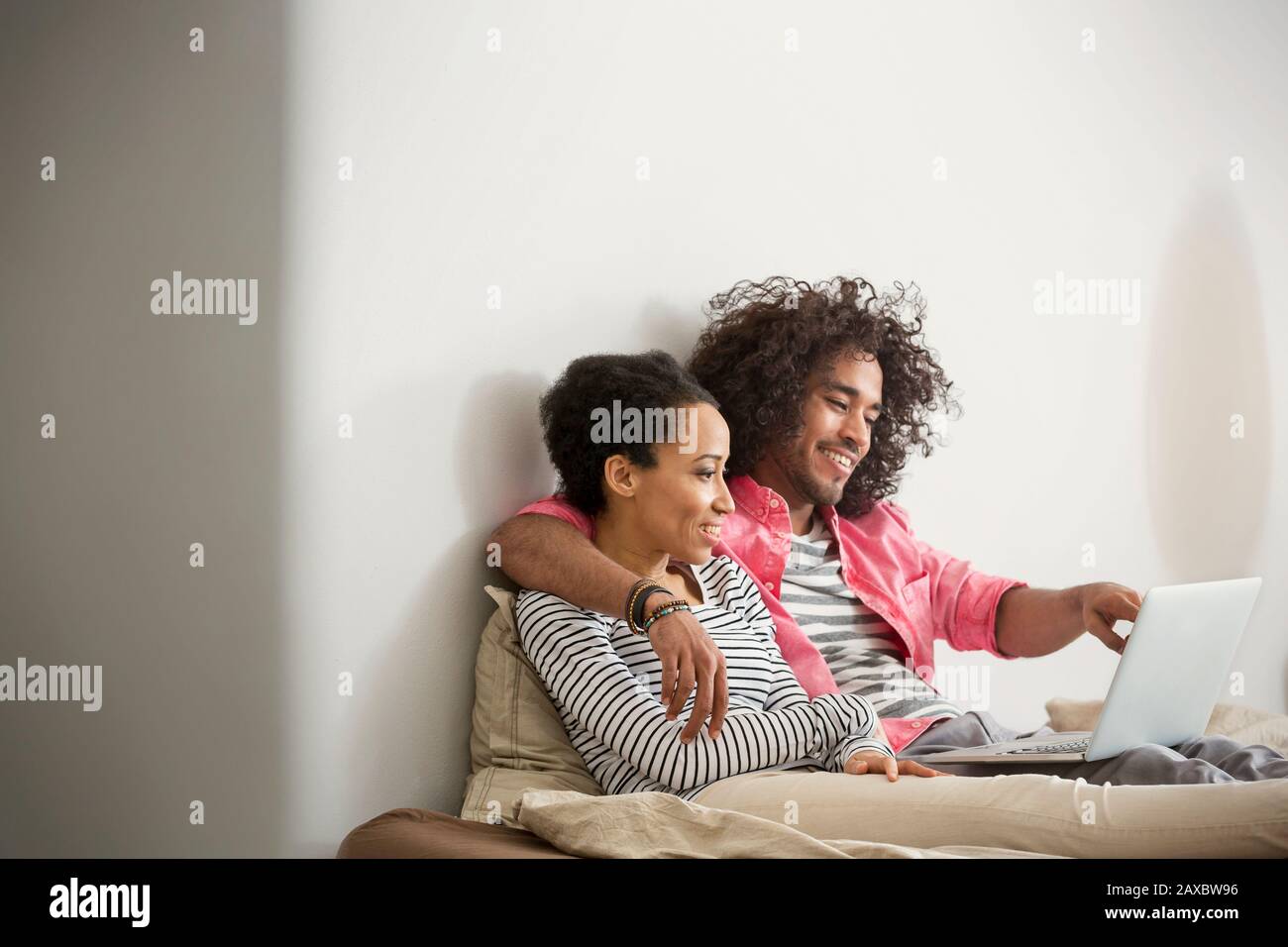 Happy, affectionate couple using laptop on bed Stock Photo