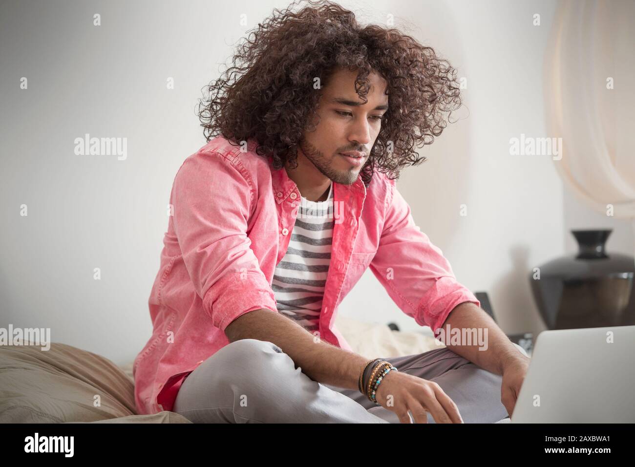 Young man working at laptop on bed Stock Photo