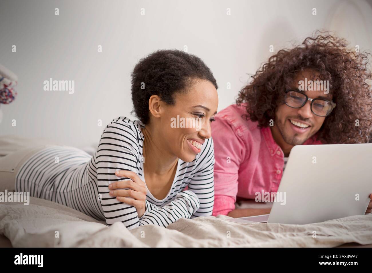 Smiling couple using laptop on bed Stock Photo
