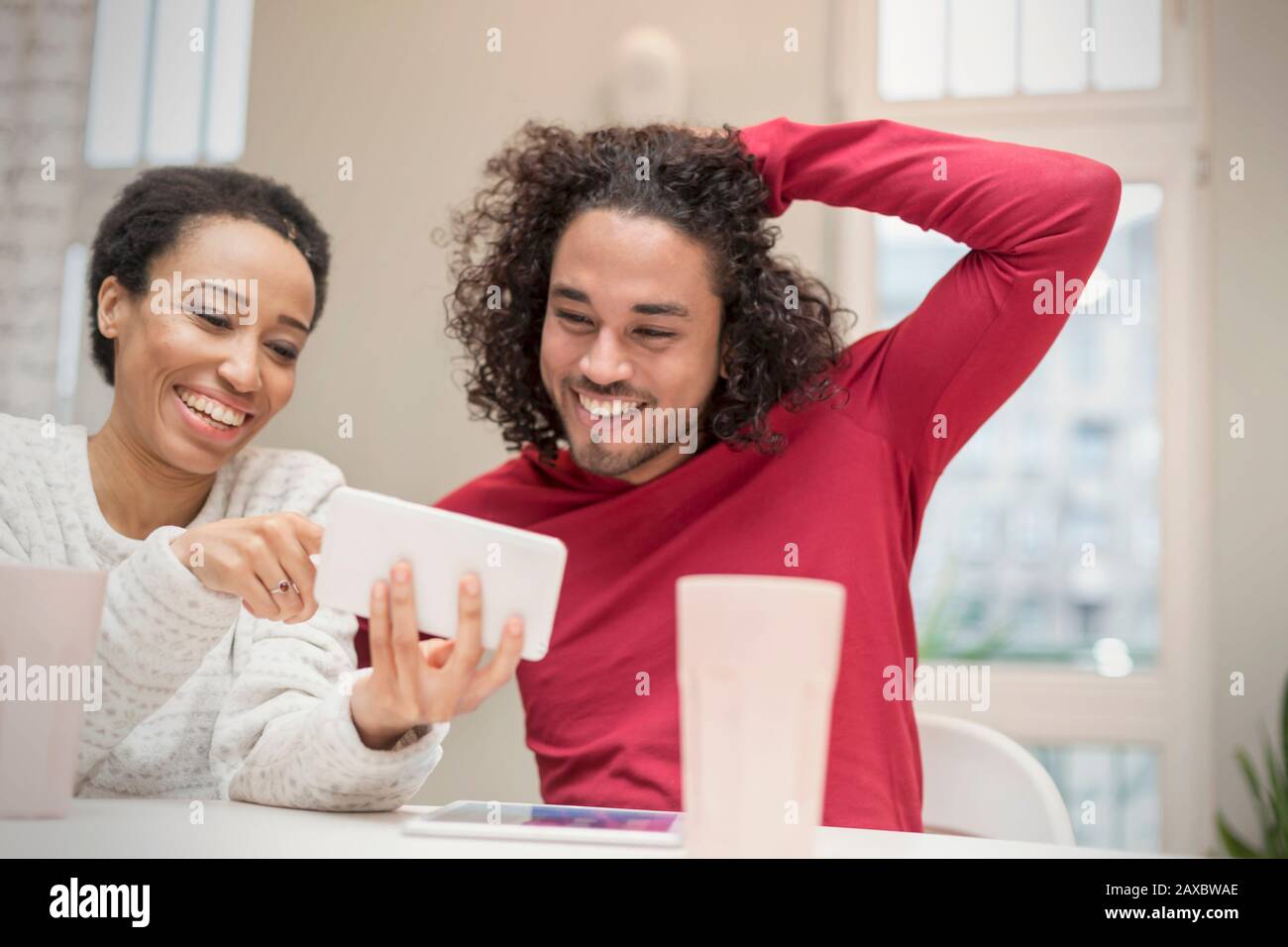 Happy couple using smart phone at table Stock Photo