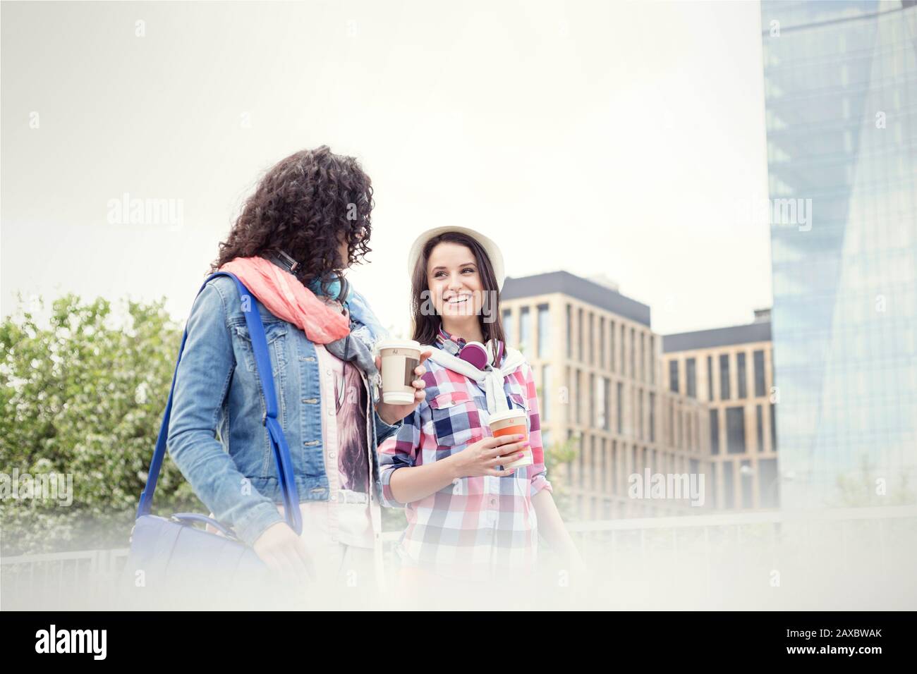 Young women friends with coffee walking in city Stock Photo