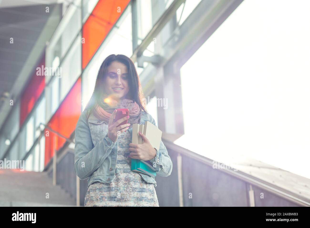 Young woman with books and smart phone descending stairs Stock Photo