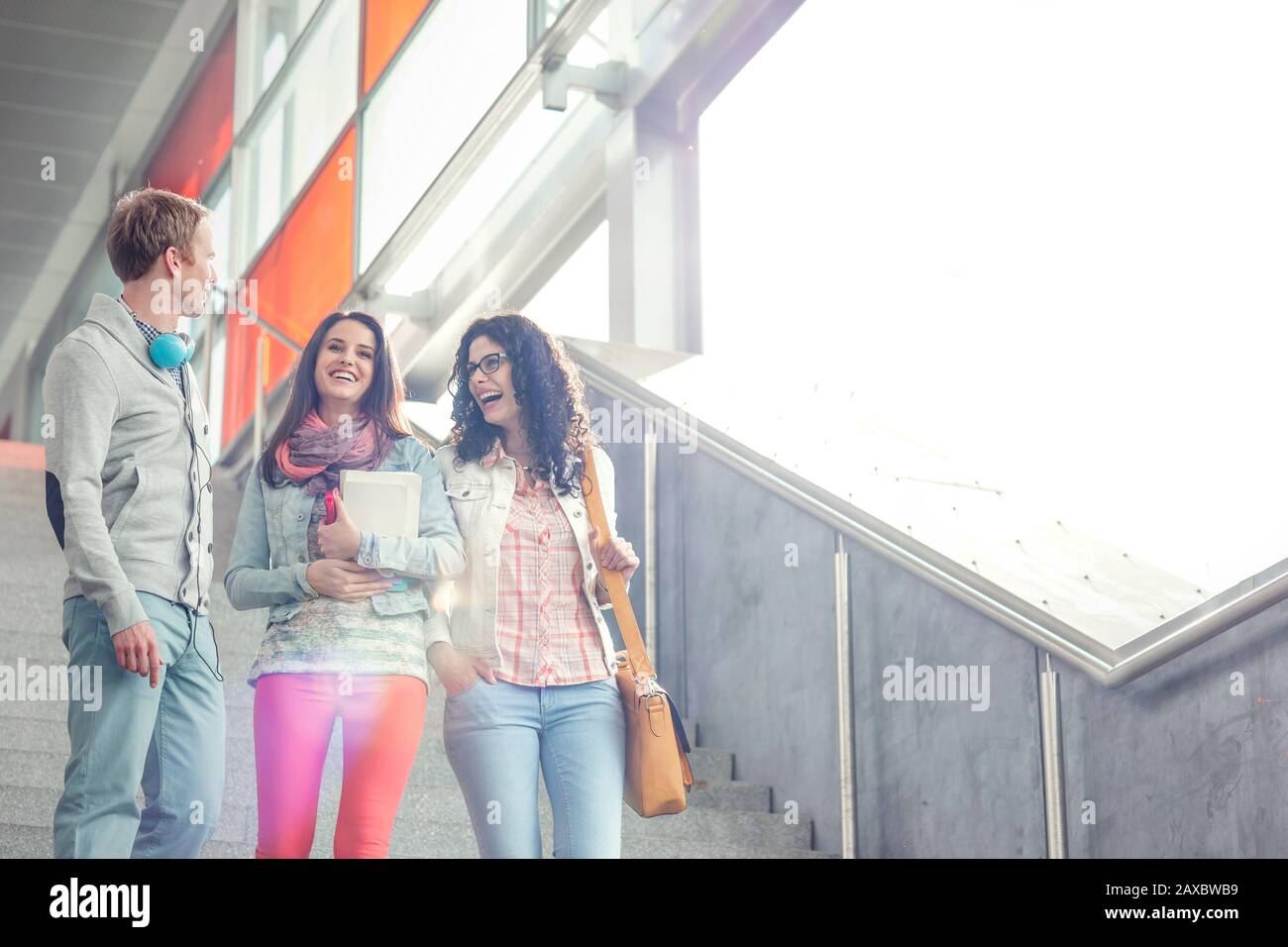 Young friends laughing, descending urban stairs Stock Photo
