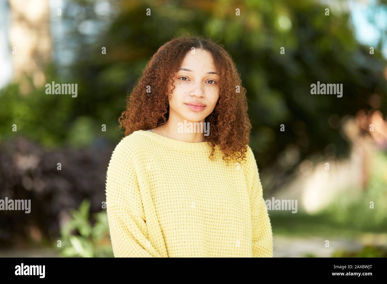 Portrait confident young woman in yellow sweater Stock Photo