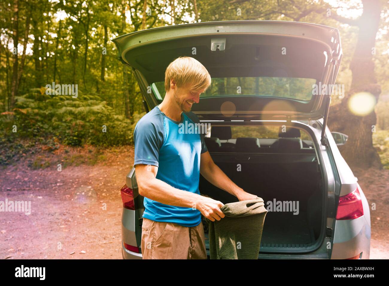 Smiling man preparing for hike at back of sunny car Stock Photo
