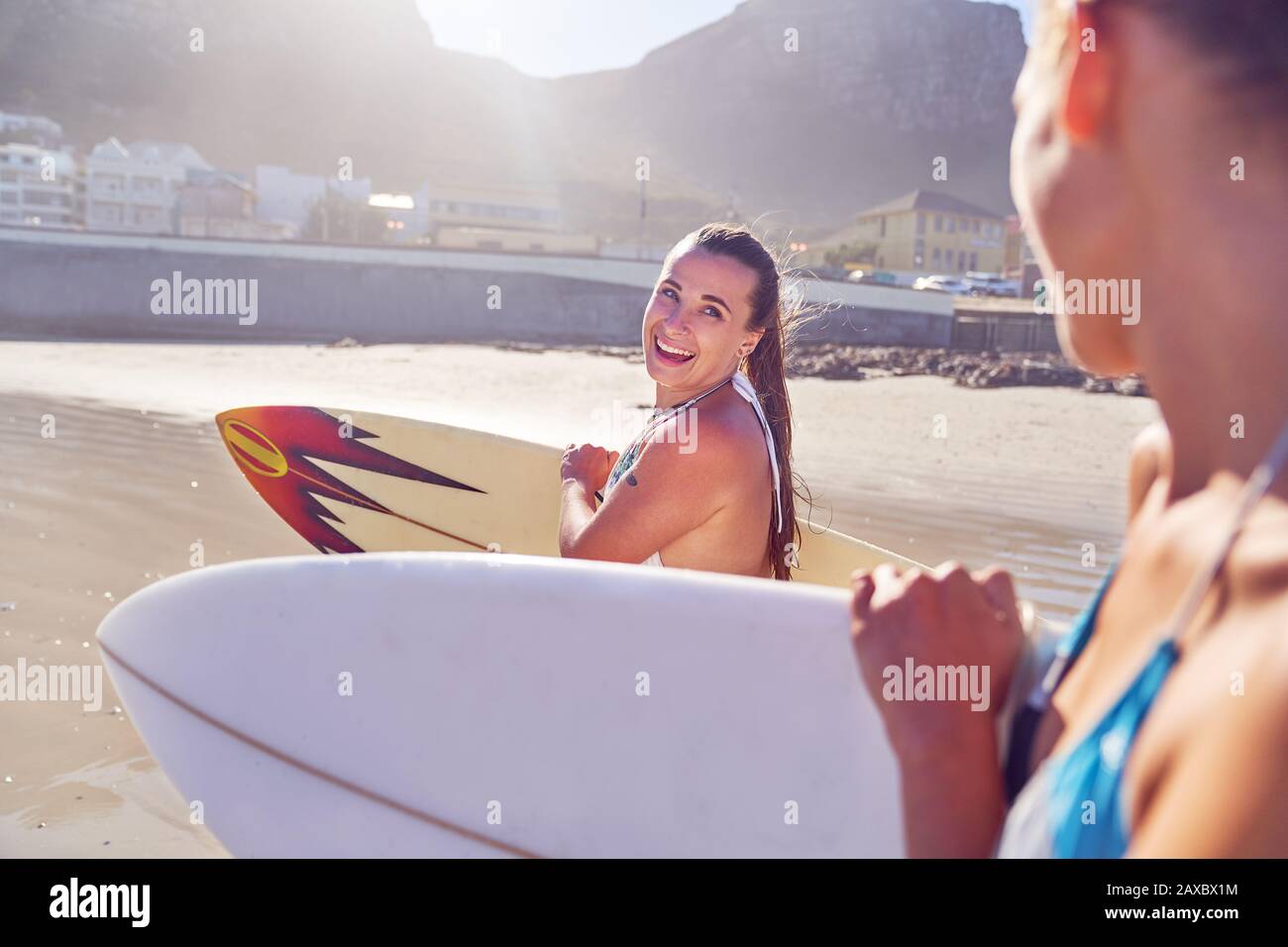 Happy young female surfer friends with surfboards on beach Stock Photo