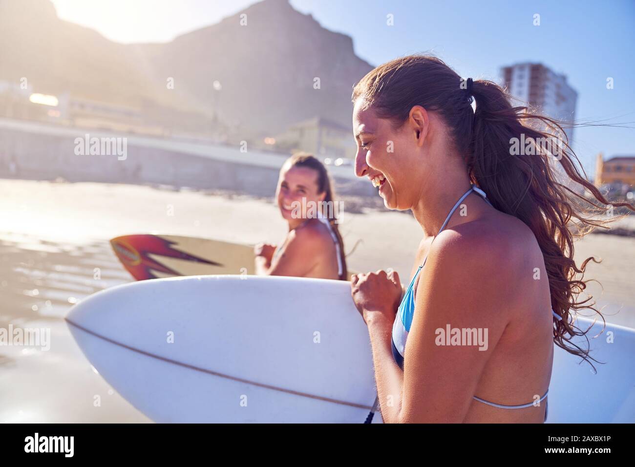 Happy young women friends with surfboards on sunny beach Stock Photo